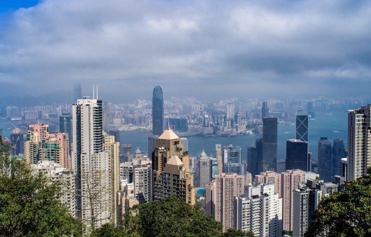 A high angle shot of a cityscape with a lot of tall skyscrapers under the cloudy sky in Hong Kong