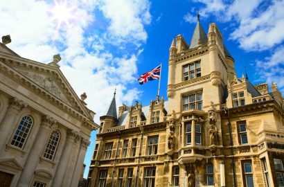 A beautiful view of historic buildings with a Union Jack flag under a bright blue sky in Cambridge, England.